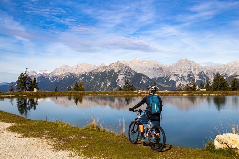 Mountain biker descansando no lago Kaltwassersee em Seefeld/Tyrol, com pico coberto de neve ao fundo