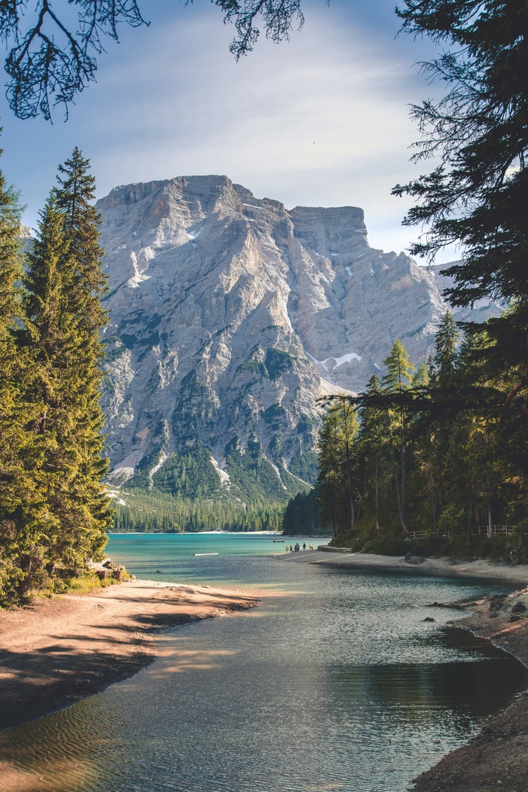 Alpine lake surrounded by coniferous forest with towering rocky mountain in the background