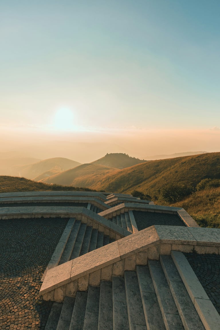 Modern dam structure across valley during golden hour sunset with rolling hills and mountains in background